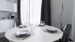 A modern dining area with a round table set for four, including plates, glasses, and cutlery. - Italianway - Corso Como 11 (Milan)