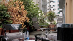 An outdoor seating area with tables and chairs, surrounded by potted plants and a backdrop of a building. - Italianway - Corso Como 11 (Milan)