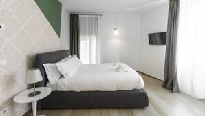 A modern hotel room with a bed, a bedside table, a TV, and a window with curtains. - Italianway - Corso Como 11 (Milan)