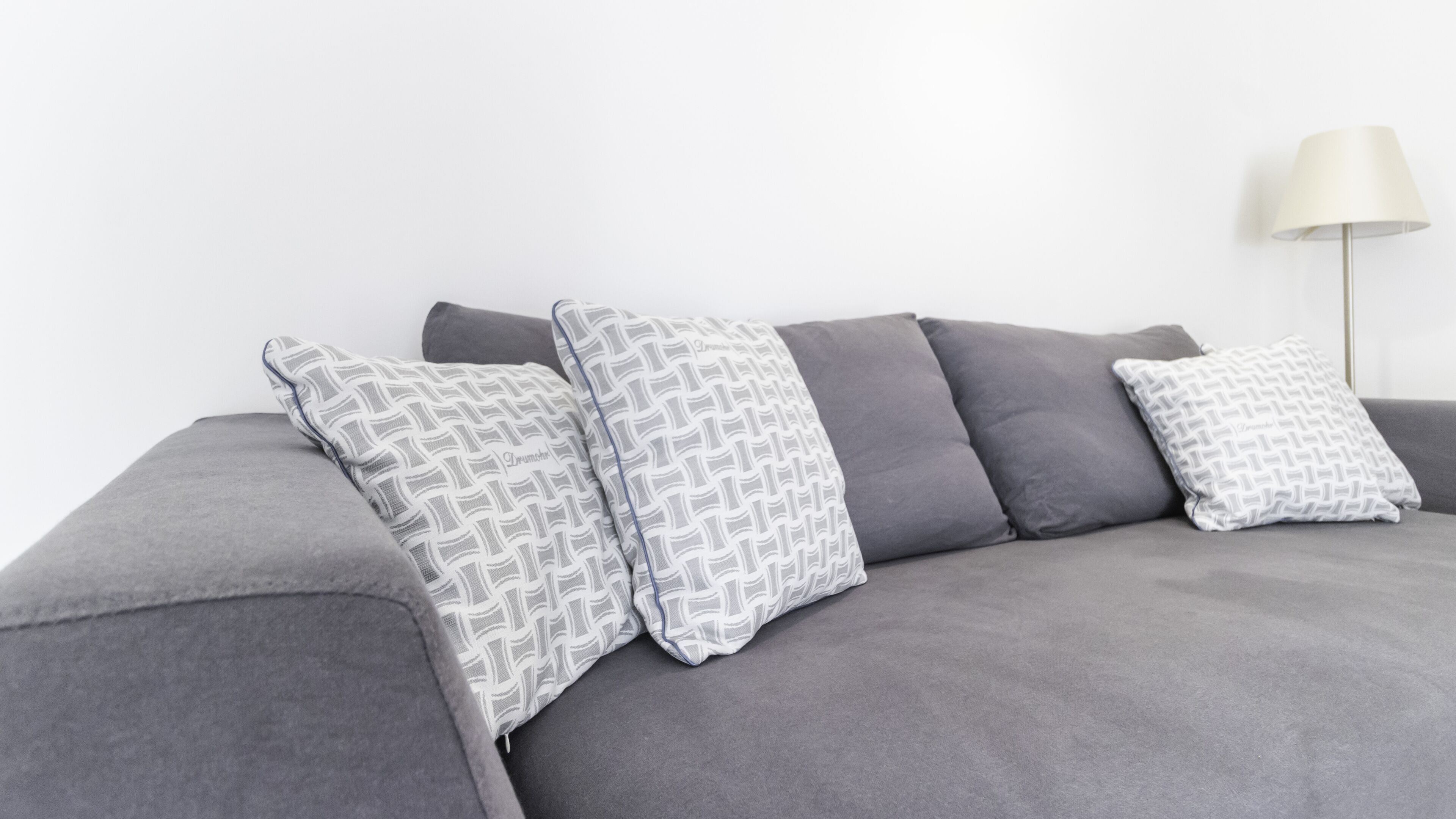 Un canapé gris agrémenté de coussins à motifs et d’un lampadaire.