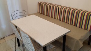 Un petit espace de restauration privatif, avec une table et des chaises, un banc doté d’un coussin à rayures et une chaise en métal.