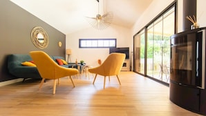 A modern living room with a large window, a flat-screen TV, and two yellow armchairs. - Villa Javal à Ares avec piscine chauffée (du 01/05 au 15/10) (Arès)