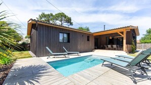 A modern house with a wooden exterior, a swimming pool, and outdoor furniture. - Villa Javal à Ares avec piscine chauffée (du 01/05 au 15/10) (Arès)