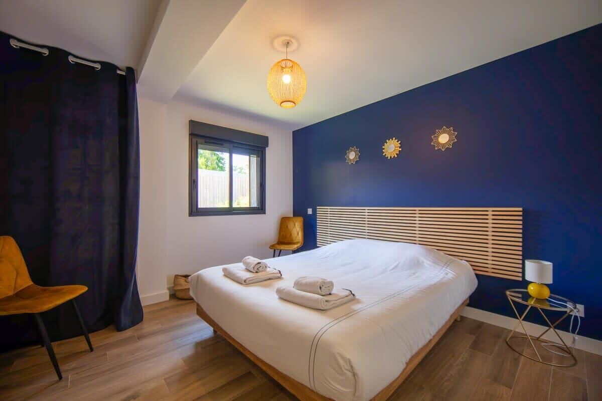 Ein Schlafzimmer mit einem großen Bett, einem Fenster, einem Sessel und einer Lampe.