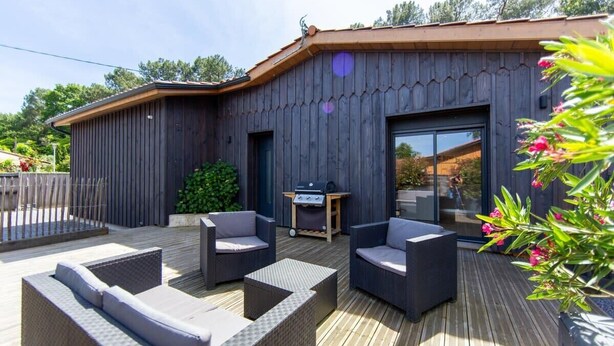 A wooden building with a deck, outdoor furniture, and a barbecue area. - Villa Javal à Ares avec piscine chauffée (du 01/05 au 15/10) (Arès)