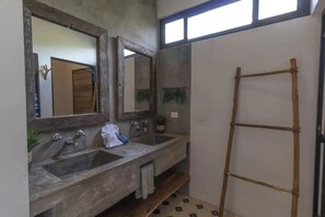 A bathroom with two sinks, a wooden ladder, and a large mirror.
