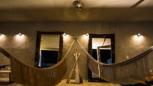 A room with a hammock, a wooden chair, and a ceiling fan. There are three doors and a light fixture on the wall. - Casa Macarena 2-BR (Tulum)