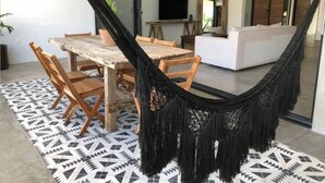 A modern living space with a dining area, a hammock, and a patterned rug. - Casa Macarena 2-BR (Tulum)