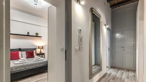 Hotellihuone, jossa on sänky, yöpöytälamppu ja suuri peili.