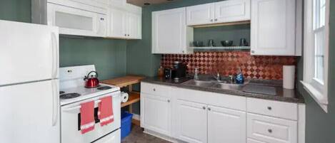 A kitchen with white cabinets, a stove, and a sink.