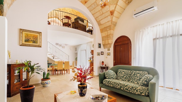 A spacious living area with a high ceiling, a green sofa, a dining table, and a staircase leading to an upper level. - 3278 Guest House Eleonora - Family by BarbarHouse (Alliste)