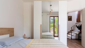 A bedroom with a bed, a nightstand, a mirror, and a staircase leading to a balcony. - 3278 Guest House Eleonora - Family by BarbarHouse (Alliste)
