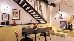 Eine moderne Küche mit Essbereich, einer Treppe und Kunstwerken an den Wänden.