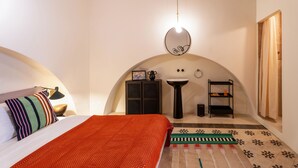 Ein Schlafzimmer mit einem Bett, einem Nachttisch, einem Spiegel, einem kleinen Waschbecken und einem Regal.
