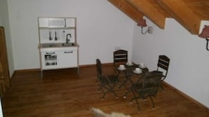 Un pequeño comedor con una mesa y sillas, un armario blanco con un lavabo y un techo de madera.