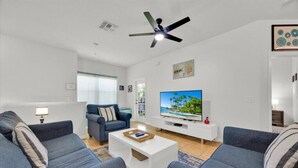 A modern living room with two grey sofas, a white coffee table, a flat-screen TV, and a ceiling fan. - Pretty & Welcoming Resort Condo (Kissimmee)