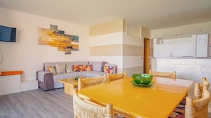 Ein modernes Wohnzimmer mit Sofa, Esstisch und Küchenzeile.