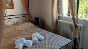 Een slaapkamer met een bed, een hanglamp, een radiator en een raam met gordijnen.