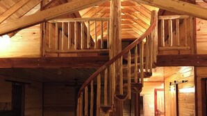 Een houten interieur met een opvallende spiraaltrap, houten wanden en een open haard.