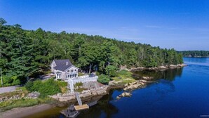 Ein Haus am See mit Steg, umgeben von dichtem Wald.