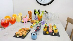 Ein Tisch, reichhaltig gedeckt mit Getränken, Snacks und Desserts, was auf ein Treffen oder eine gesellige Zusammenkunft hindeutet.