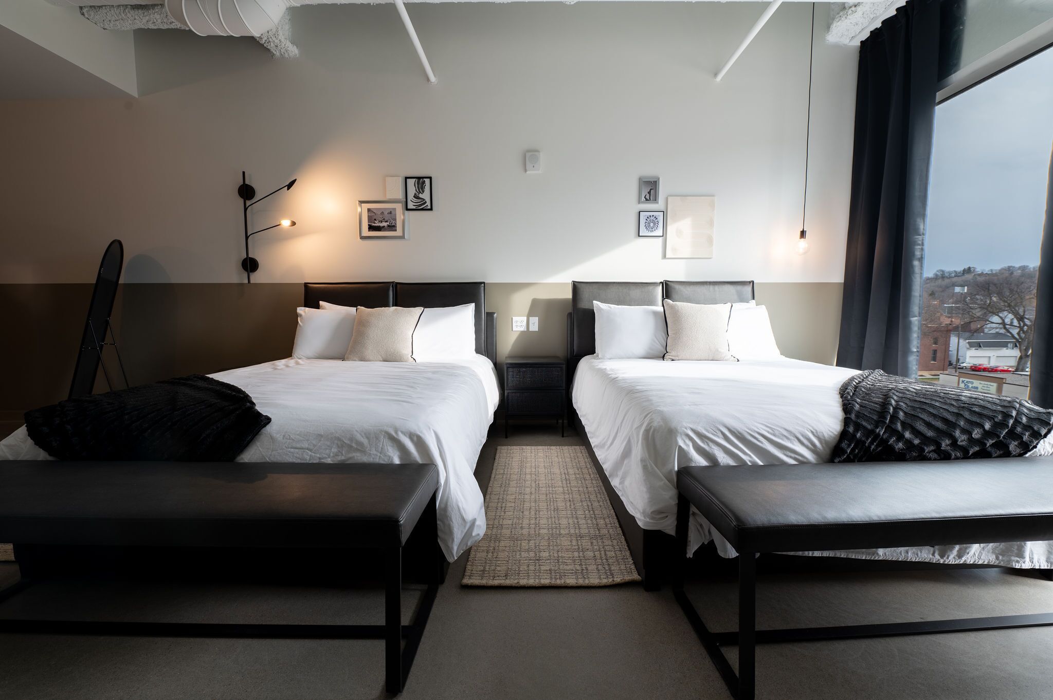 Ein Hotelzimmer mit zwei Betten, einer Bank, einem Teppich und Bildern an der Wand.