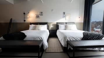 A hotel room with two beds, a bench, a rug, and artwork on the walls.