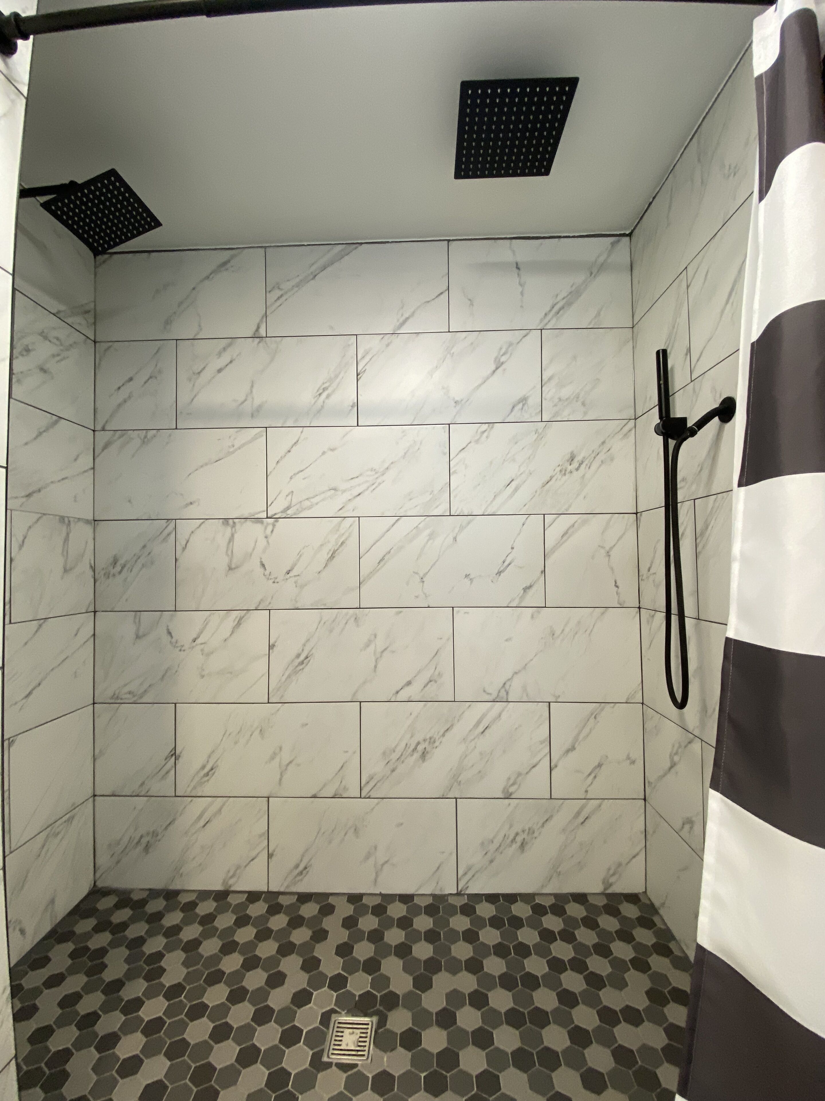 Un espace douche avec des carreaux de marbre blanc et un sol à motifs hexagonaux.
