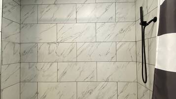 Un espace douche avec des carreaux de marbre blanc et un sol à motifs hexagonaux.