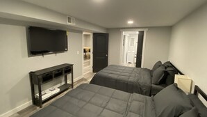 Ein Schlafzimmer mit zwei Betten, einem Fernseher und einem Schreibtisch.