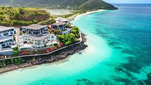 A coastal property with multiple buildings, a wooden pier, and a view of the turquoise sea and distant mountains. - Tamarind Hills Resort - Ocean Blessed (Antigua and Barbuda)
