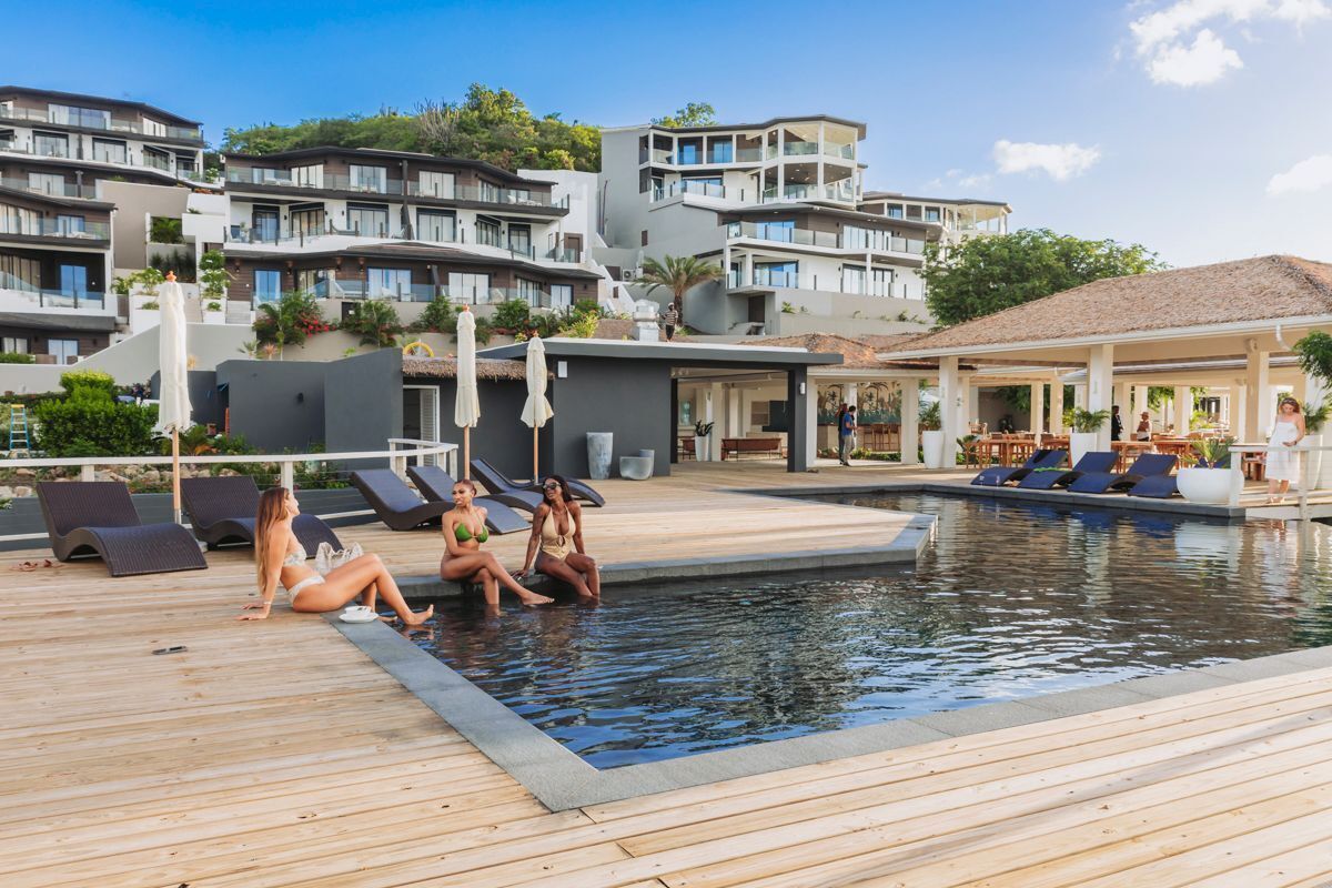 A poolside area with lounge chairs and a pool, surrounded by modern buildings with balconies.