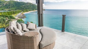 A wicker sofa with cushions on a balcony overlooking a beach and ocean. - Tamarind Hills Resort - Barracuda 8 (Antigua and Barbuda)