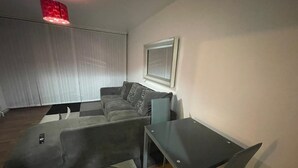 A modern living room with a grey sofa, a glass coffee table, and a red pendant light. - New! Xtra Large 4 Bedroom Up to 14 Guests (London)