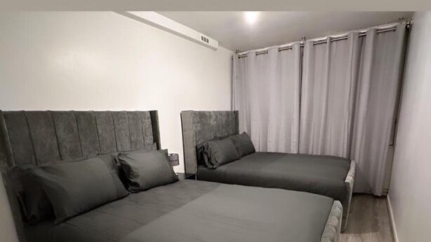 A bedroom with two beds, each with a headboard and pillows. - New! Xtra Large 4 Bedroom Up to 14 Guests (London)