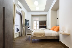 A bedroom with a bed, a desk, a chair, a TV, and a skylight.