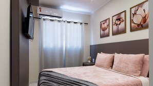 A bedroom with a bed, a nightstand, a TV, and an air conditioner. - Hotel Gigante Beach Itapema (Itapema)