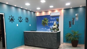A reception area with a marble counter, a blue wall with nautical-themed decorations, and a tropical-themed poster. - Hotel Gigante Beach Itapema (Itapema)