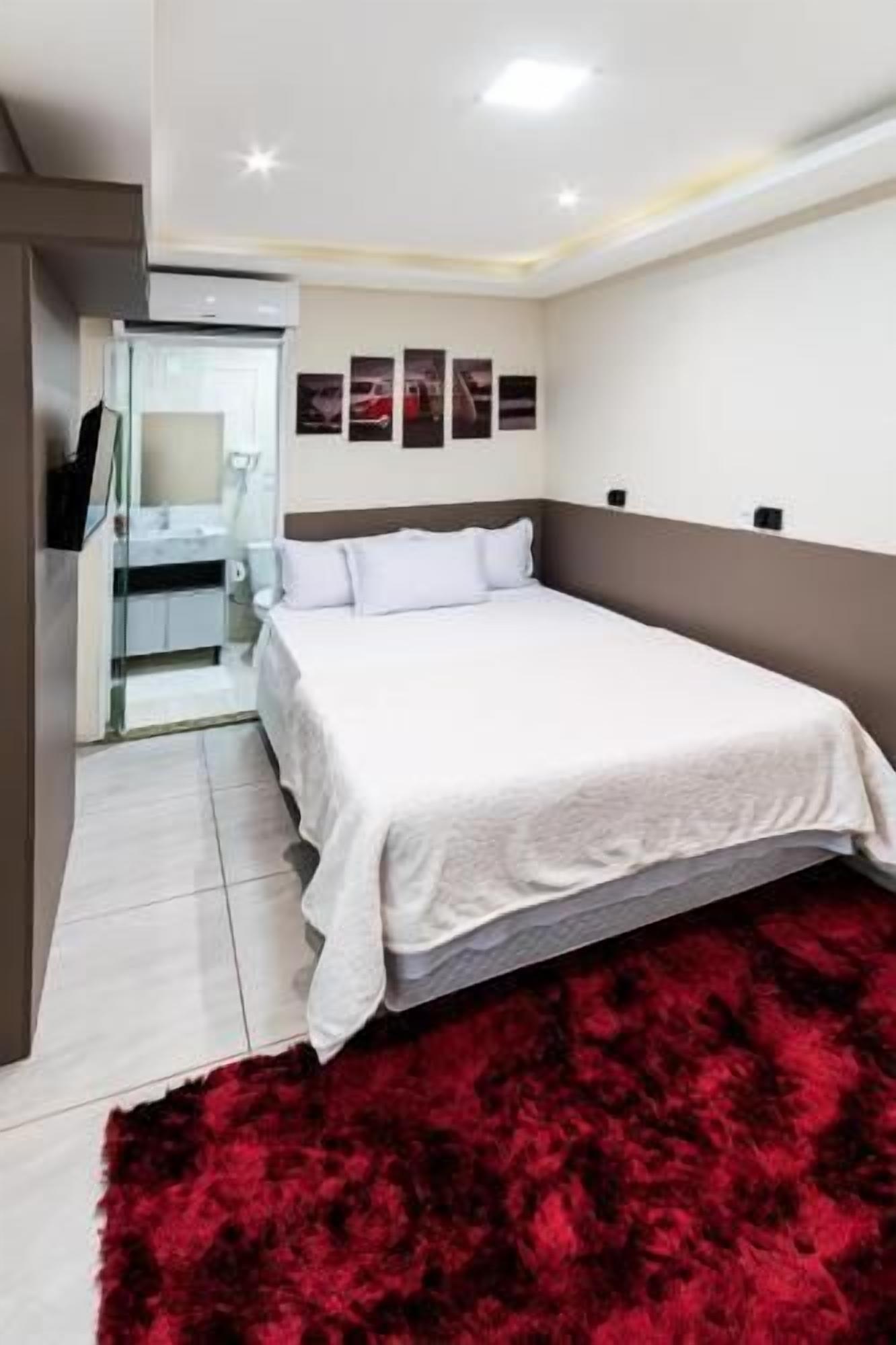 Quarto com cama, tapete vermelho, guarda-roupa e espelho.