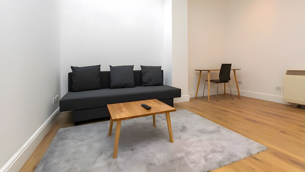 Ein modernes Wohnzimmer mit einer schwarzen Couch, einem Holztisch und einem kleinen Tisch mit einem Stuhl.