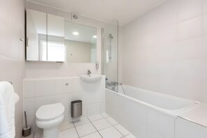 A modern bathroom with a toilet, sink, and bathtub.