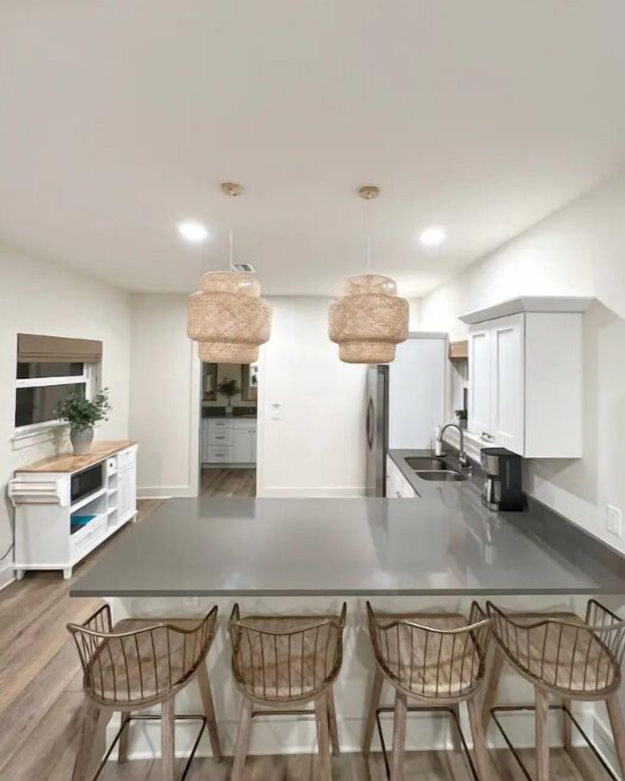 A modern kitchen with a central island, white cabinetry, and a dining area with four chairs.