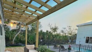 An outdoor patio with wicker furniture and a glass coffee table.