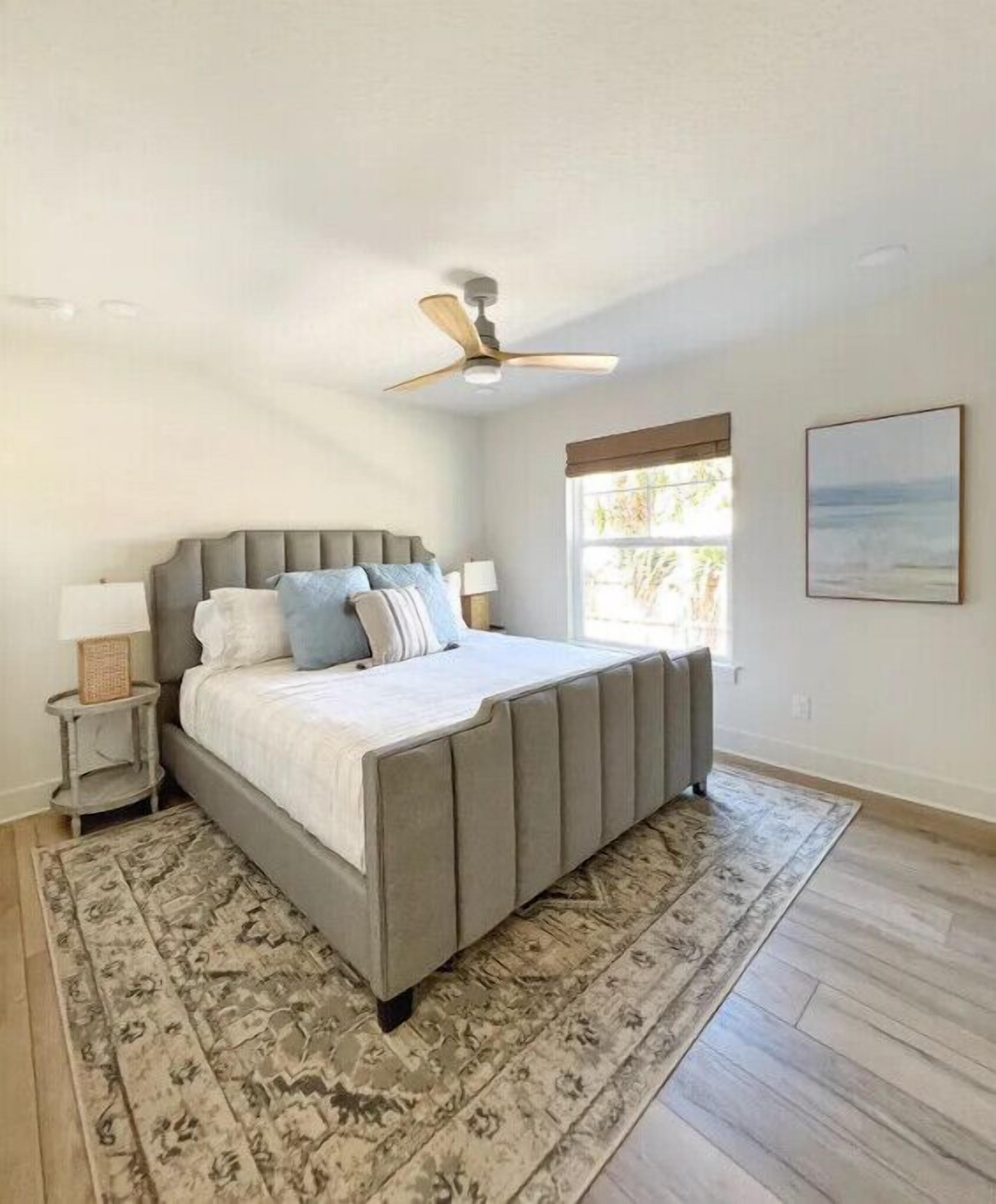 A bedroom with a bed, a ceiling fan, a window, and a rug.