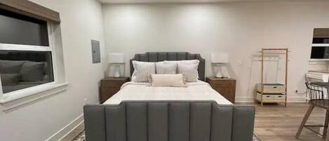 Une chambre à coucher avec un grand lit, un ventilateur de plafond, des lampes de chevet, une table de chevet, une armoire et une fenêtre.