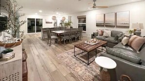 A modern living room with a dining area, leather sofa, and a coffee table.