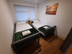 A small, compact room with two single beds, a window with blinds, a painting on the wall, and a wooden floor. - St Margaret's 2-bed Chalet - Sleeps 4 & Pets ok (Dover)