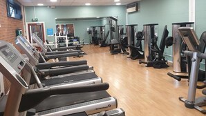 Ein Fitnessstudio mit Laufbändern, Kraftgeräten und einer Spiegelwand.