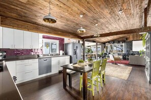 Una cocina moderna con vigas de madera en el techo, un comedor con sillas amarillas y vistas al salón.