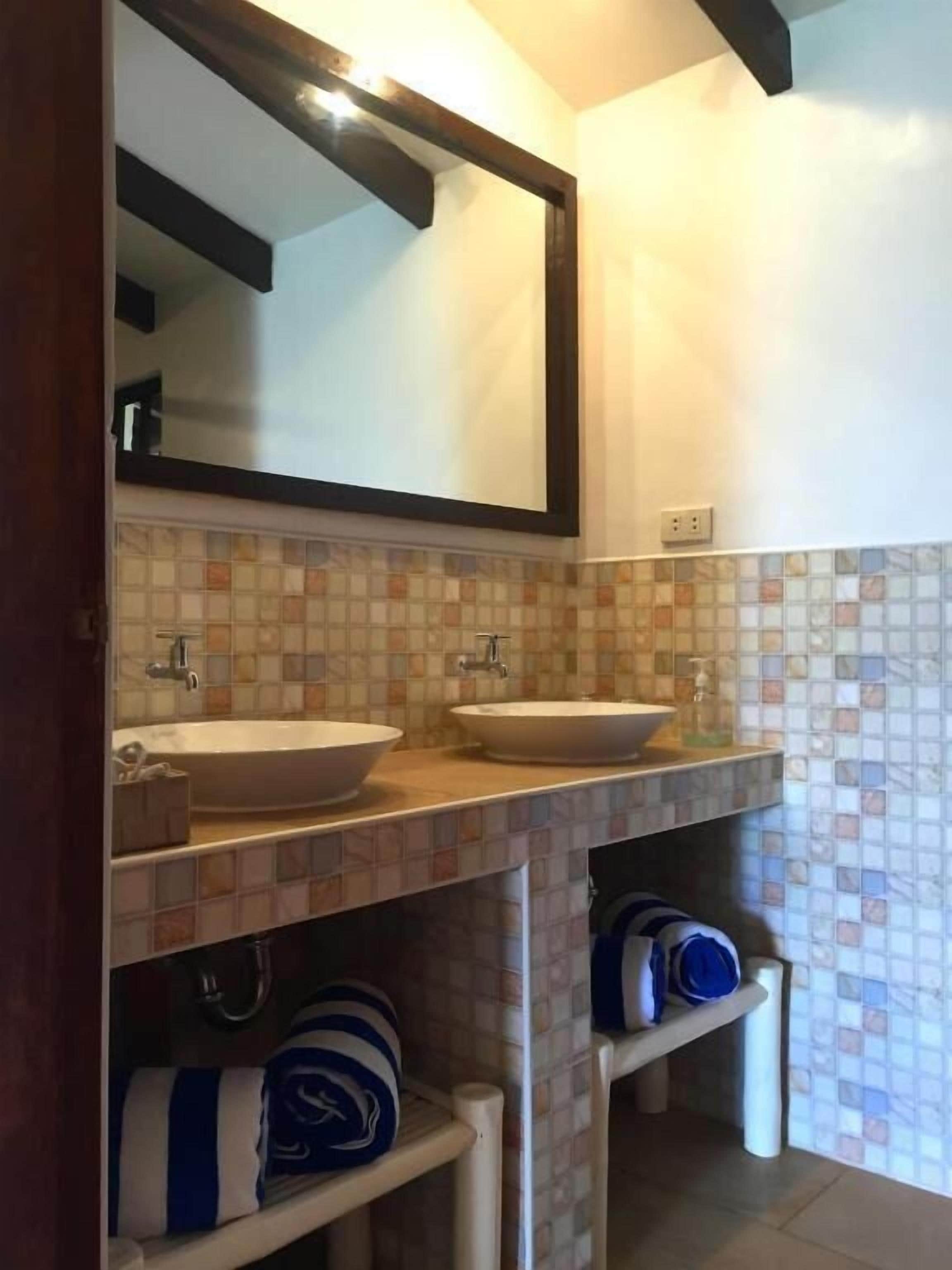 A bathroom with two sinks, a mirror, and tiled walls.